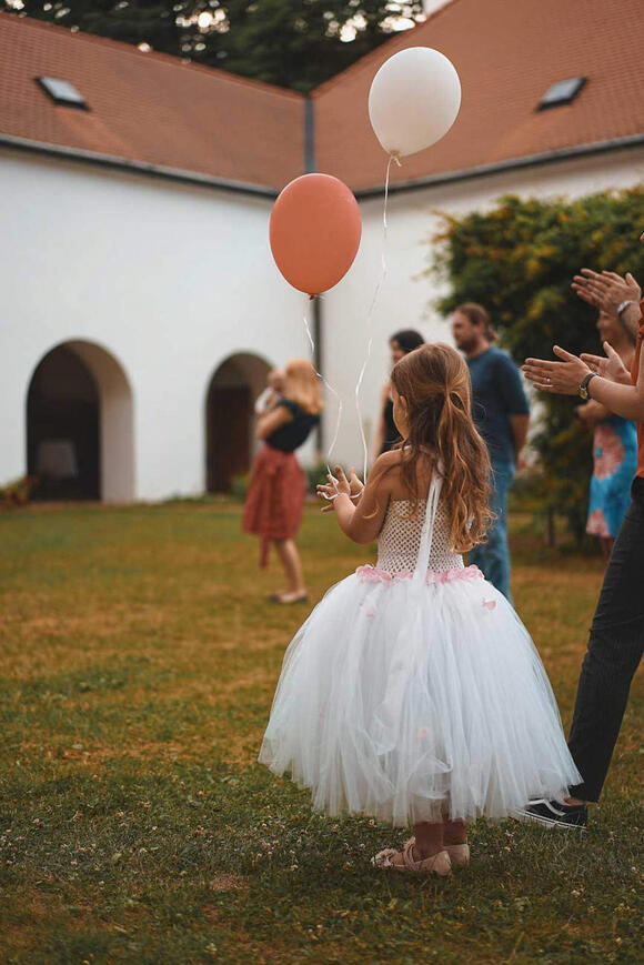 Dívka s balónky v bílých šatech