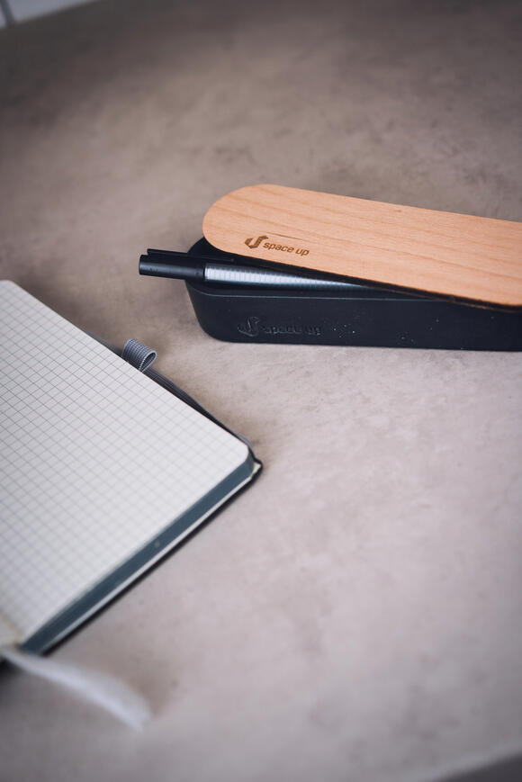 držák na tužky ležící vedle poznámkového bloku