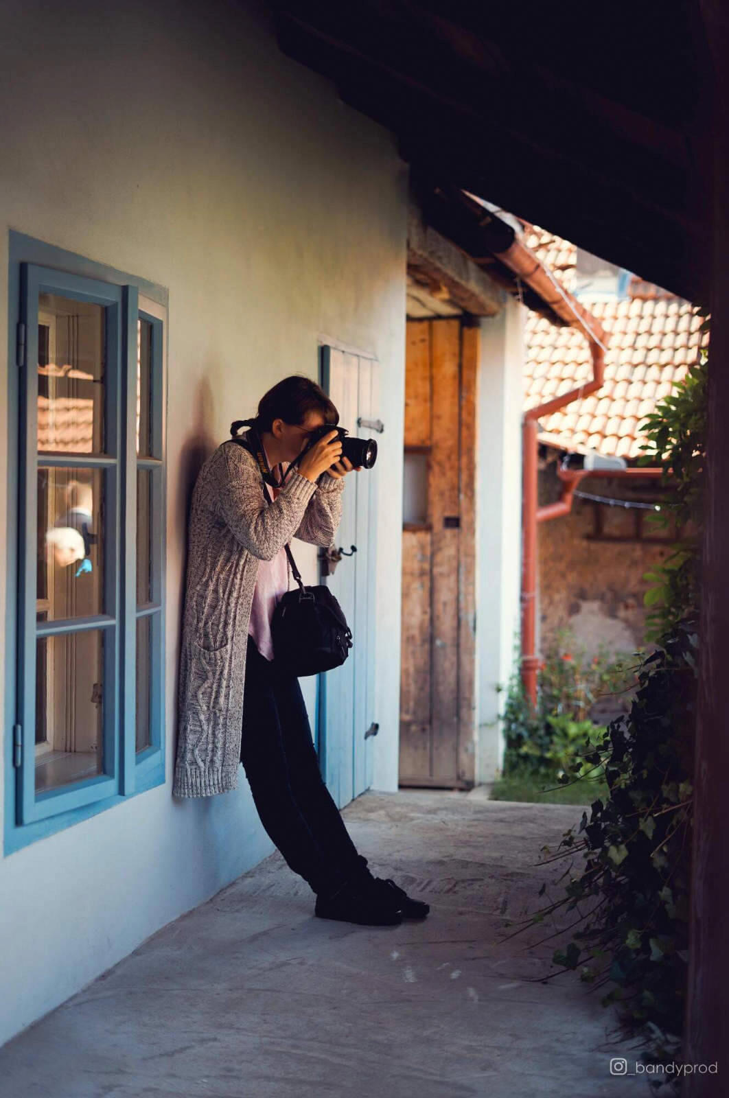 žena v kalhotách s fotoaparátem a taškou